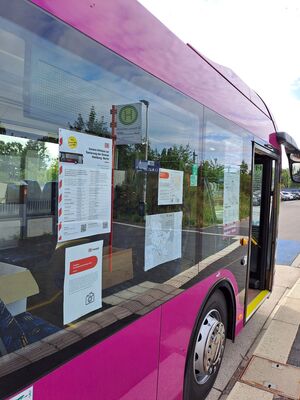Nahaufnahme eines Ersatzbusses, an dessen Fensterscheiben Fahrpläne und eine Übersichtskarte für die Zeit der Generalsanierung aufgehängt sind.