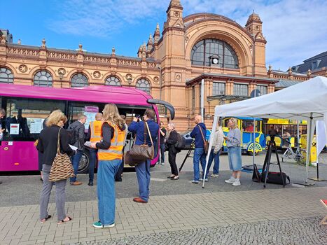 Das Projektteam der Generalsanierung Hamburg-Berlin informiert mit einem Infostand am Grunthalplatz in Schwerin. Ein Ersatzverkehrsbus steht vor dem Bahnhofseingang zur Besichtigung.